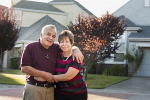 older couple looks happy in front of their home